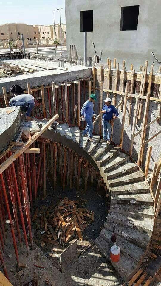 Workers and supervisors reviewing concrete staircase formwork during construction.